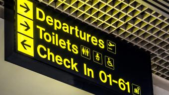 Airport sign with arrows directing to departures, toilets and check in