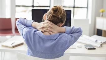 woman at desk stretching her back