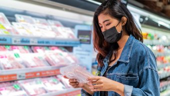 woman with mask shopping for meat